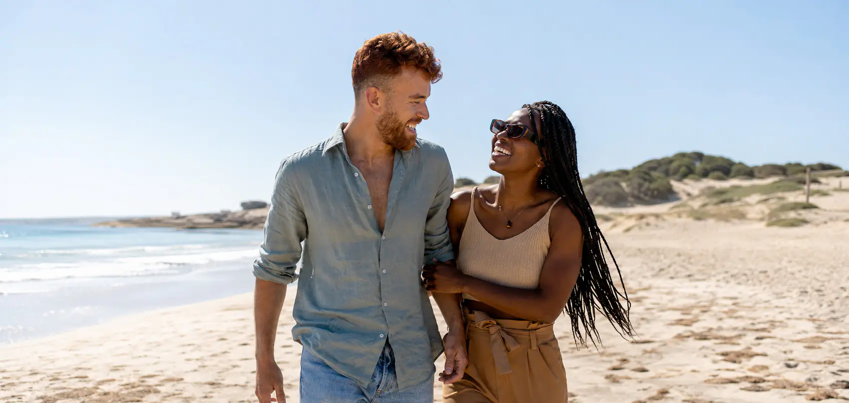 Un couple marche au bord de l'eau sur une plage du Sénégal