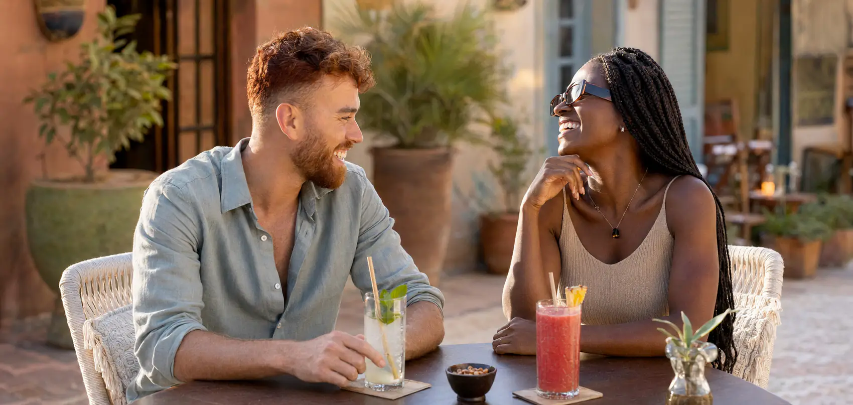 Un couple attablé en terrasse, un verre devant chacun, en pleine conversation