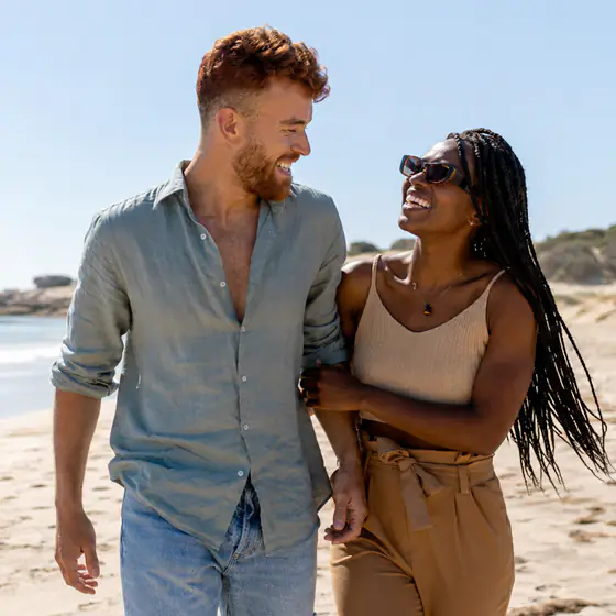 Le couple marche sur la plage en se regardant