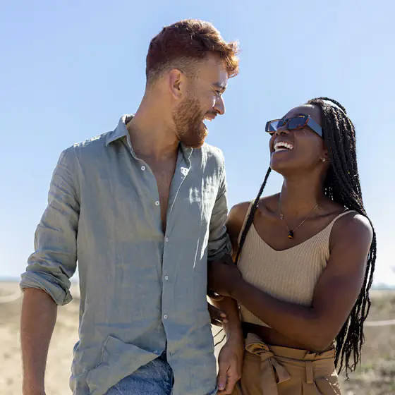 Le couple s'arrête et se sourit, la mer derrière eux