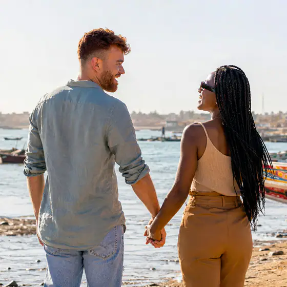 Le couple s'éloigne main dans la main, le long du rivage