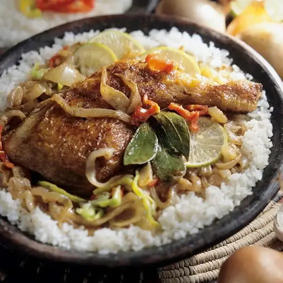 Un poisson grillé servi avec du riz et des légumes